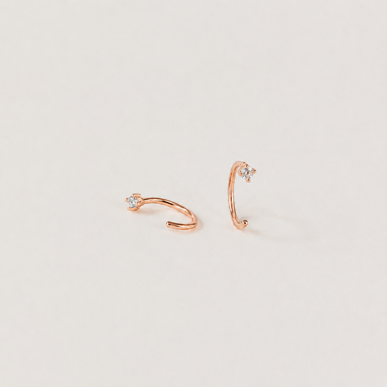 Rose gold ear cuffs with small diamonds on a light gray background